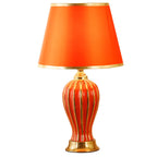 Red ceramic table lamp with fluted ceramic base on a white background