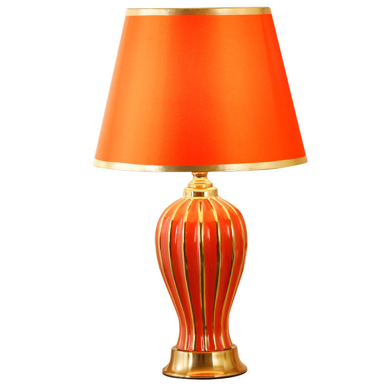 Red ceramic table lamp with fluted ceramic base on a white background