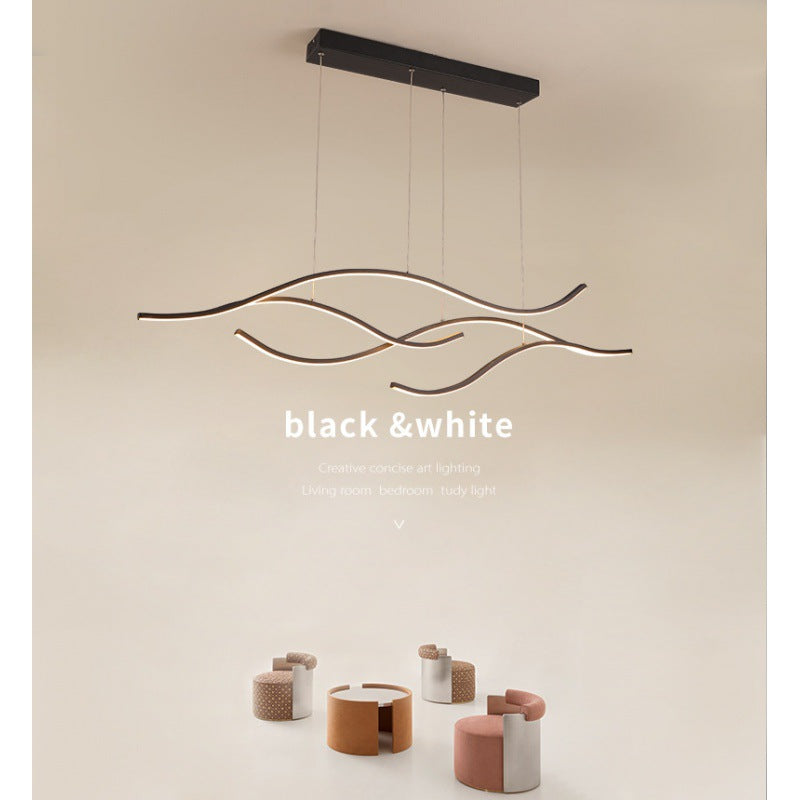 DRAPMODE modern wave-shaped LED pendant light in sand black finish, hanging over a contemporary living room set