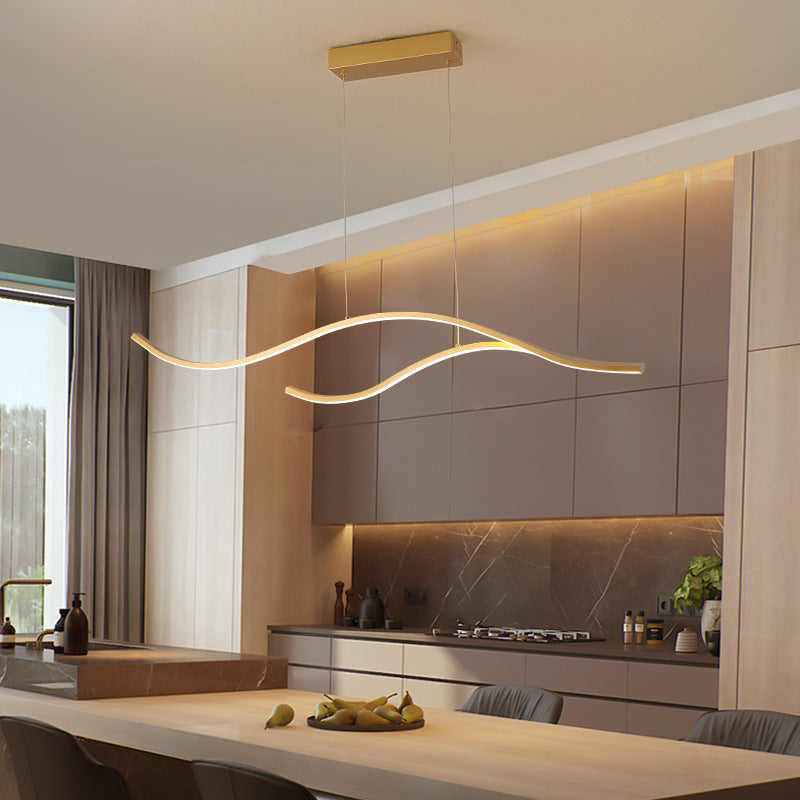 DRAPMODE modern gold wave LED pendant light hanging over a contemporary kitchen island