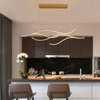 DRAPMODE modern gold wavy LED pendant light fixture hanging over a contemporary kitchen island