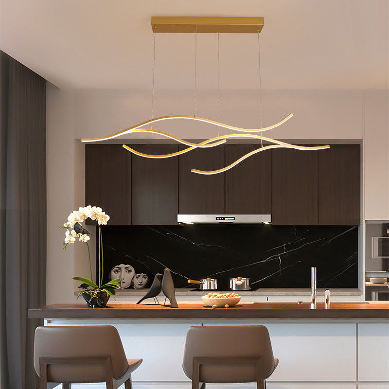 DRAPMODE modern gold wavy LED pendant light fixture hanging over a contemporary kitchen island