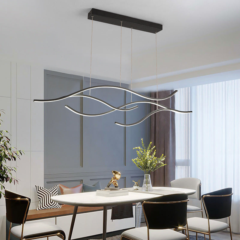 DRAPMODE modern wave-shaped LED pendant light in sand black hanging over a contemporary dining table