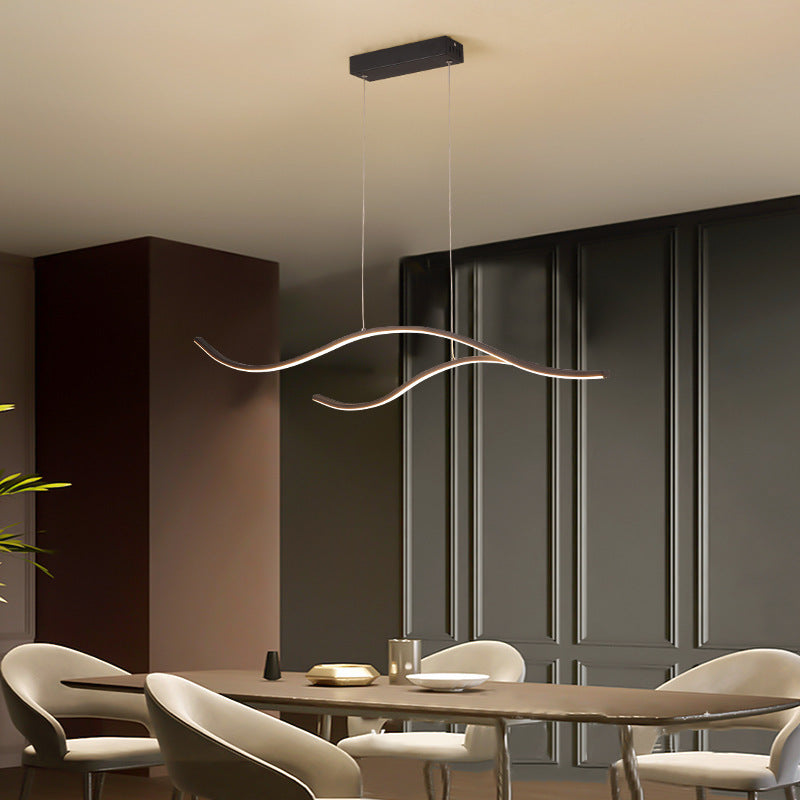 DRAPMODE modern wave-shaped LED pendant light in sand black finish hanging over a contemporary dining table