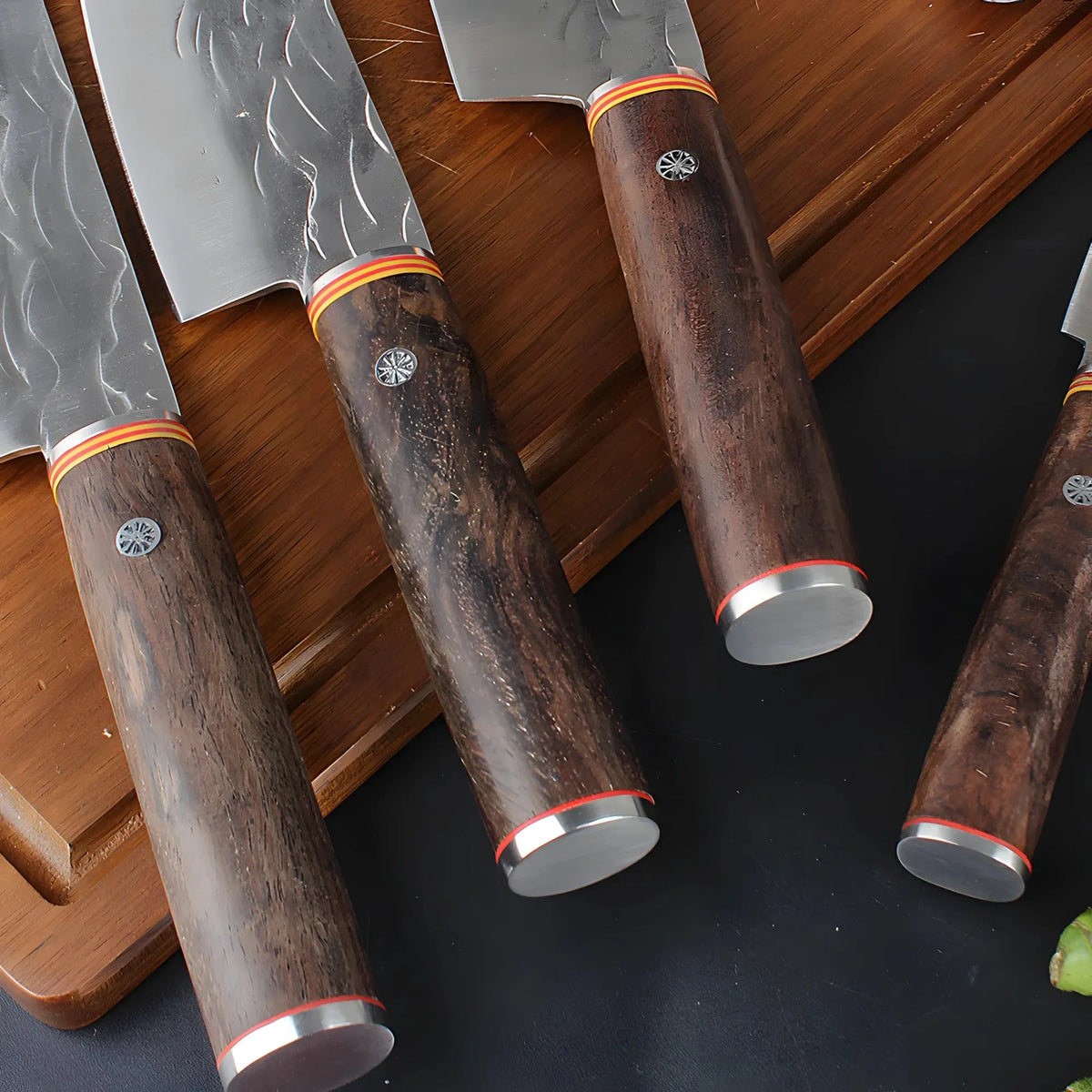 Close-up of forged knife wooden handles with metal end caps on a wooden board