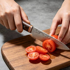 Forged chef knife slicing tomatoes on a wooden chopping board
