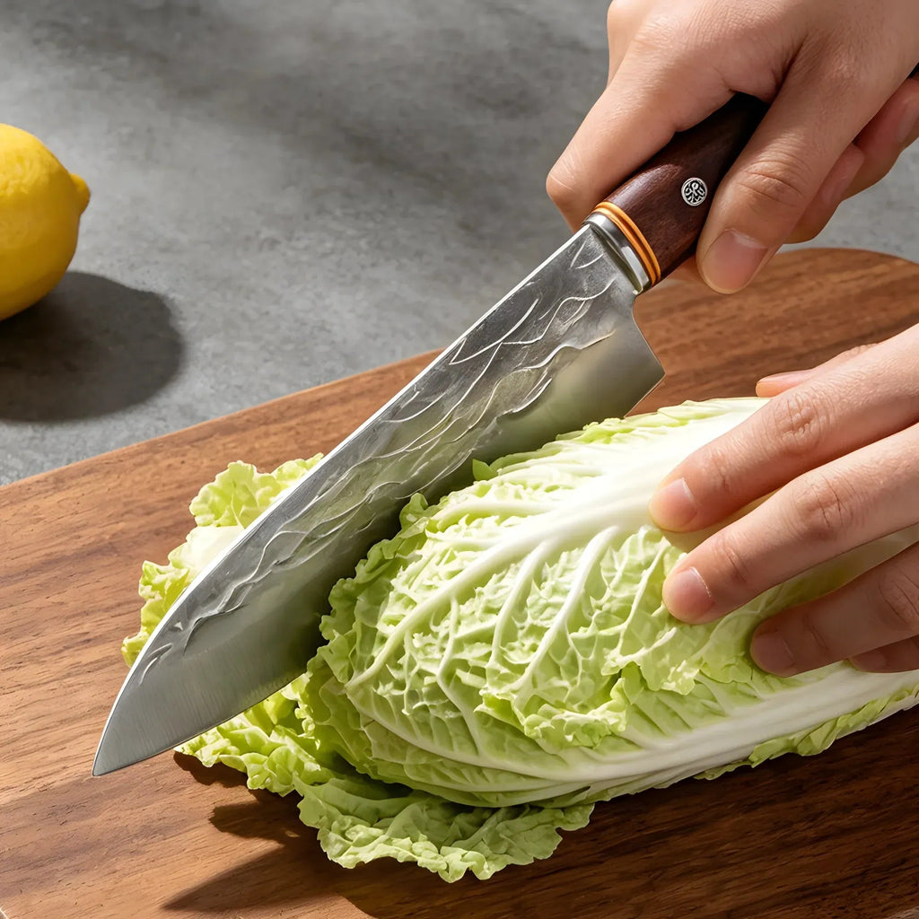 Chef knife with patterned blade slicing cabbage on a wooden chopping board