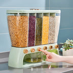Light green grain storage dispenser with six clear compartments — hand pressing a button to dispense grains into the drawer